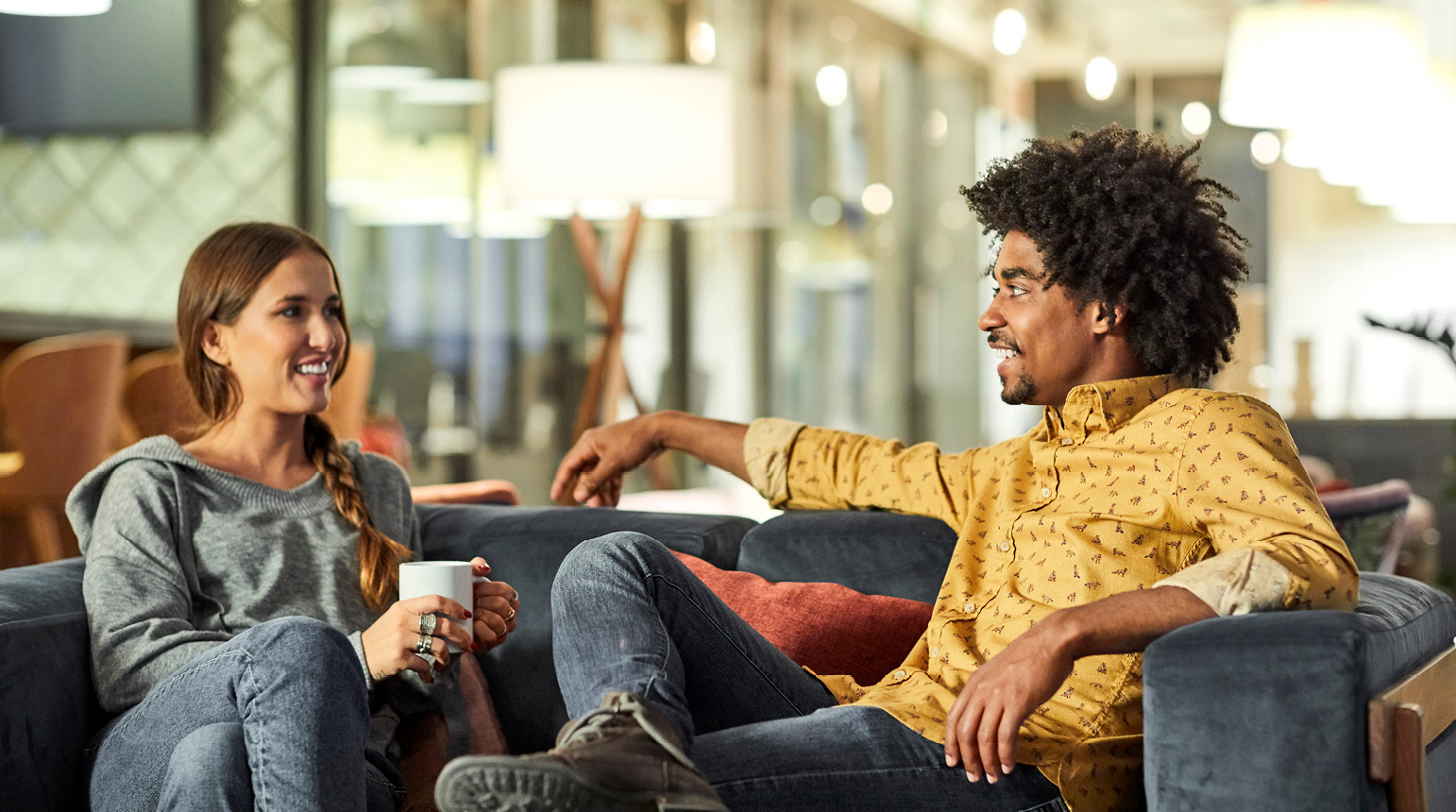 Two people talking on a couch.