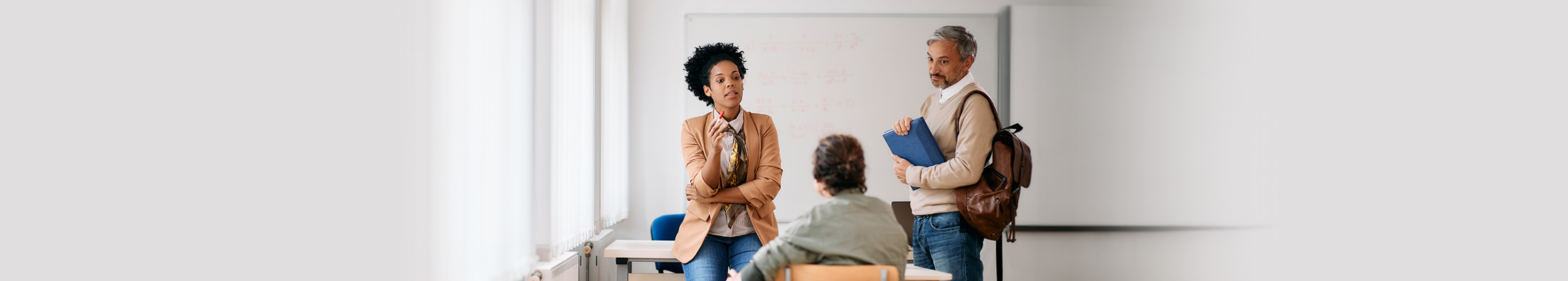 Black female teacher having consultations with adult students after a class at lecture hall.