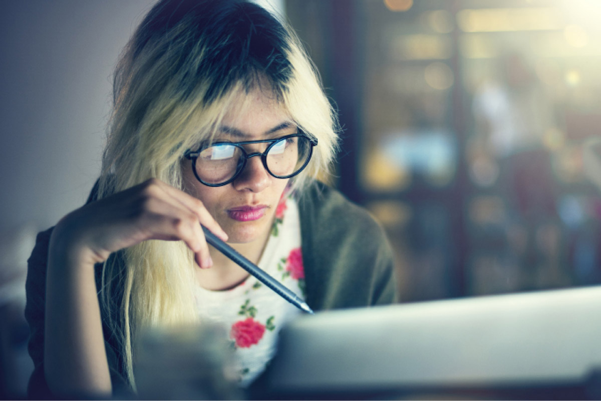 a young woman studying with the glow of the computer screen illuminating her face