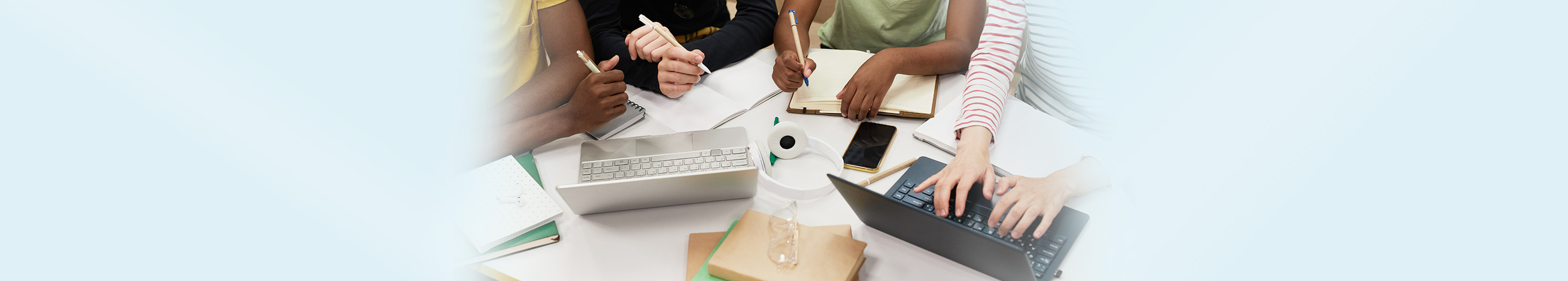 Diverse group of college students studying together at table with laptops, books, and notebooks